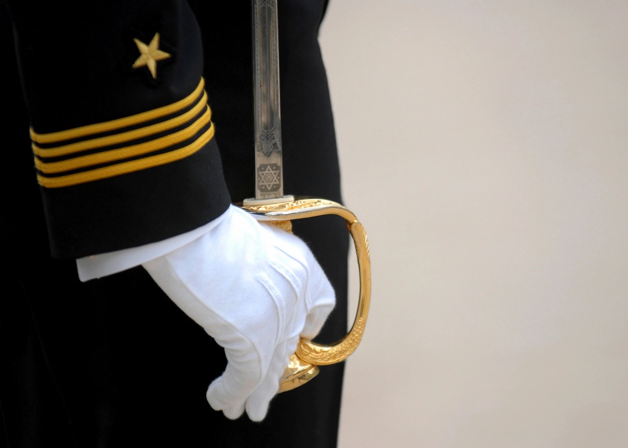 White-gloved hand holding gold sword hilt