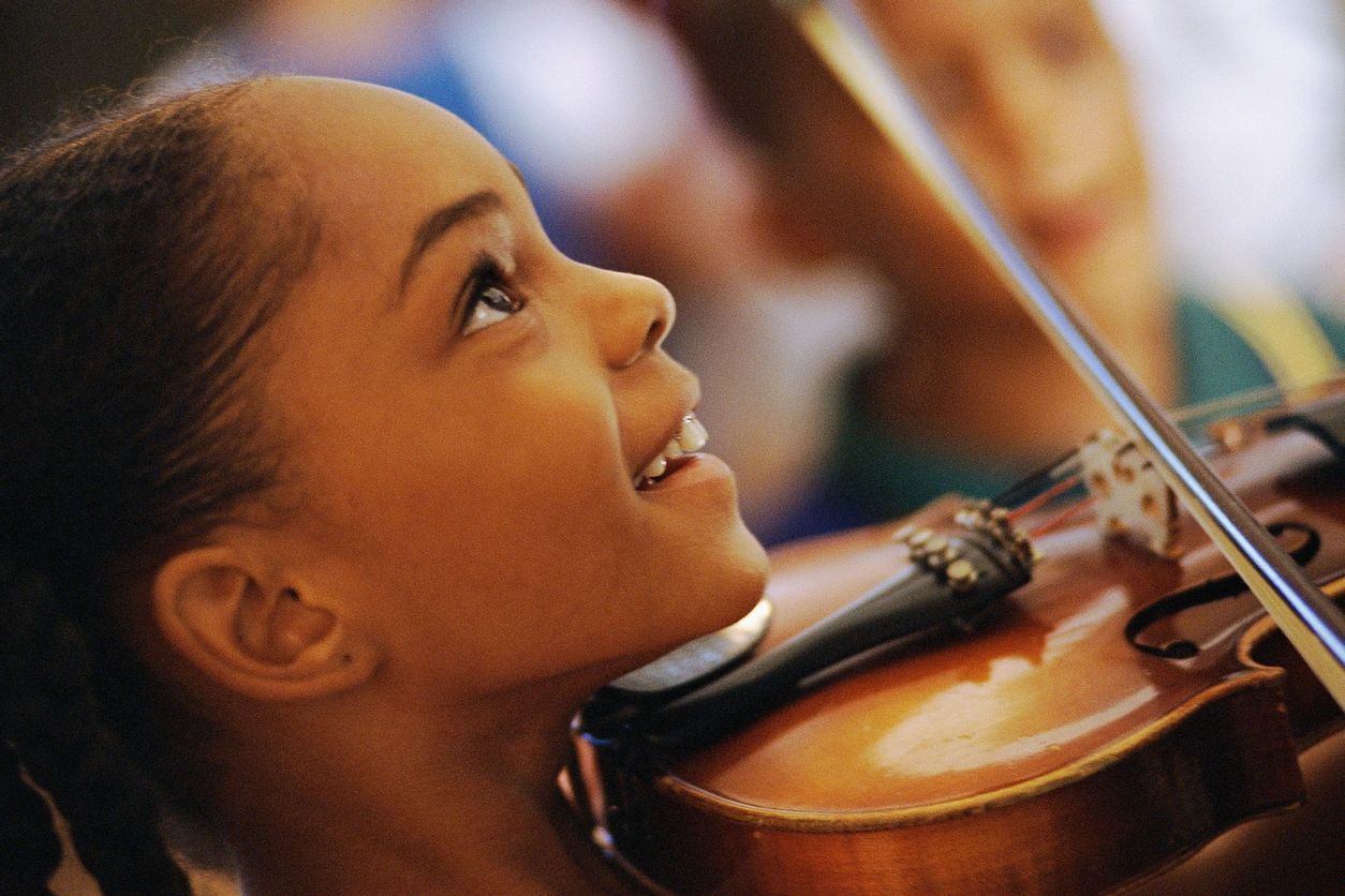 Bright-eyed girl smiling while playing violin