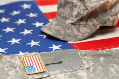 Camouflage military uniform, cap, and American flag